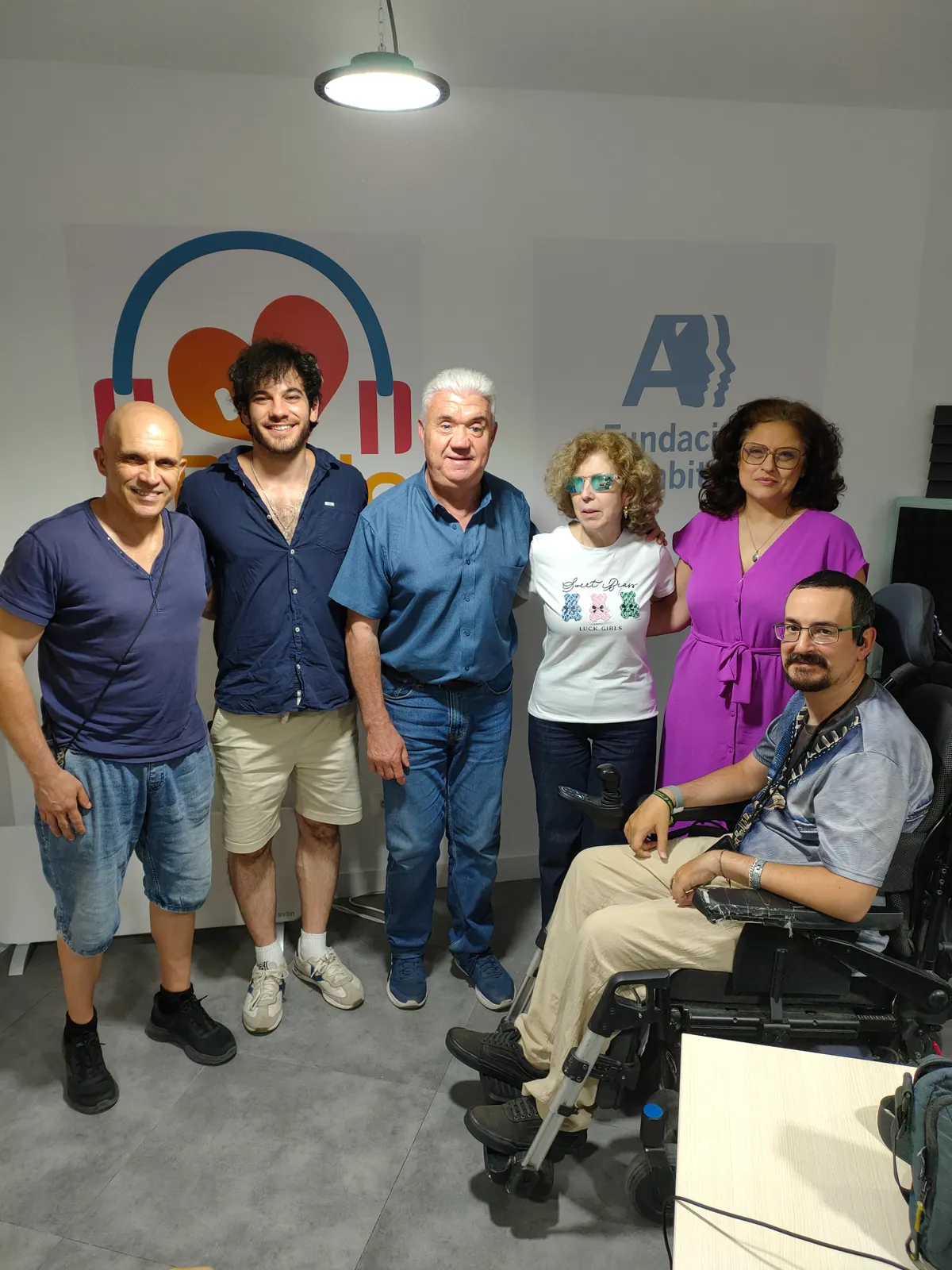 Parte del equipo de Radio Diversiones posando junto al logotipo del estudio