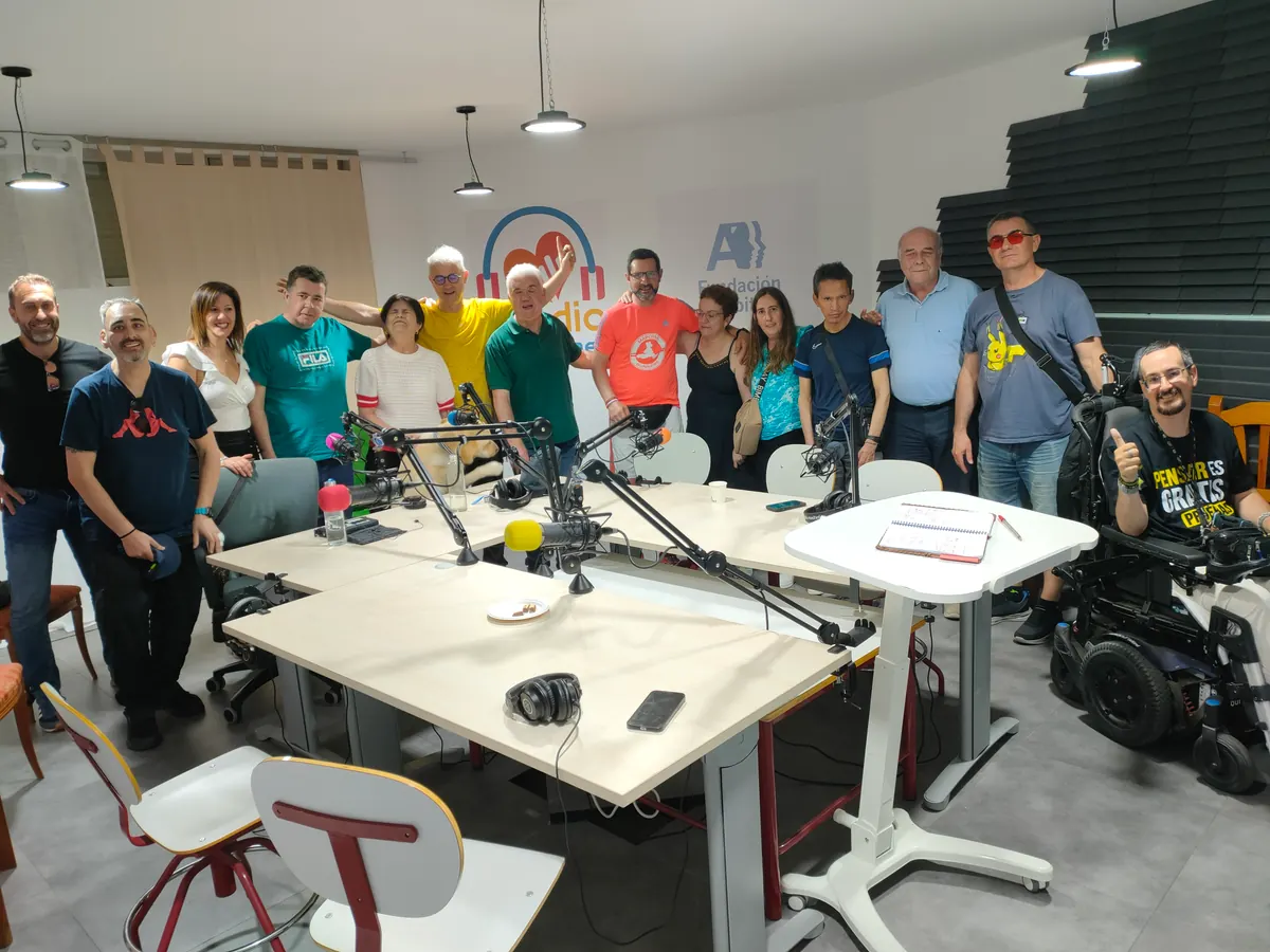Equipo de Radio Diversiones reunido en el estudio con micrófonos sobre la mesa